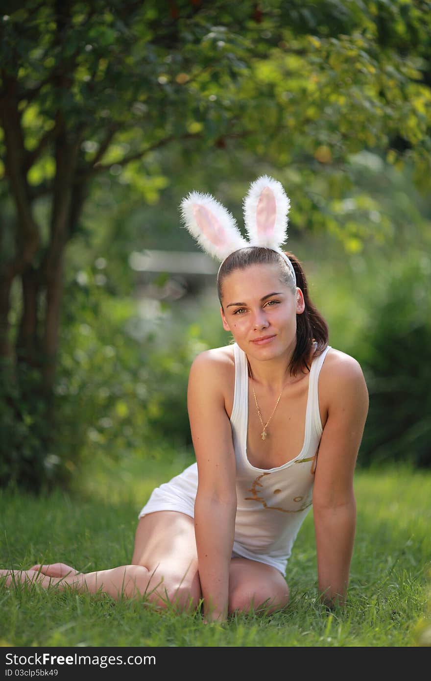 Woman with funny rabbit ears sits on a grass outdoors