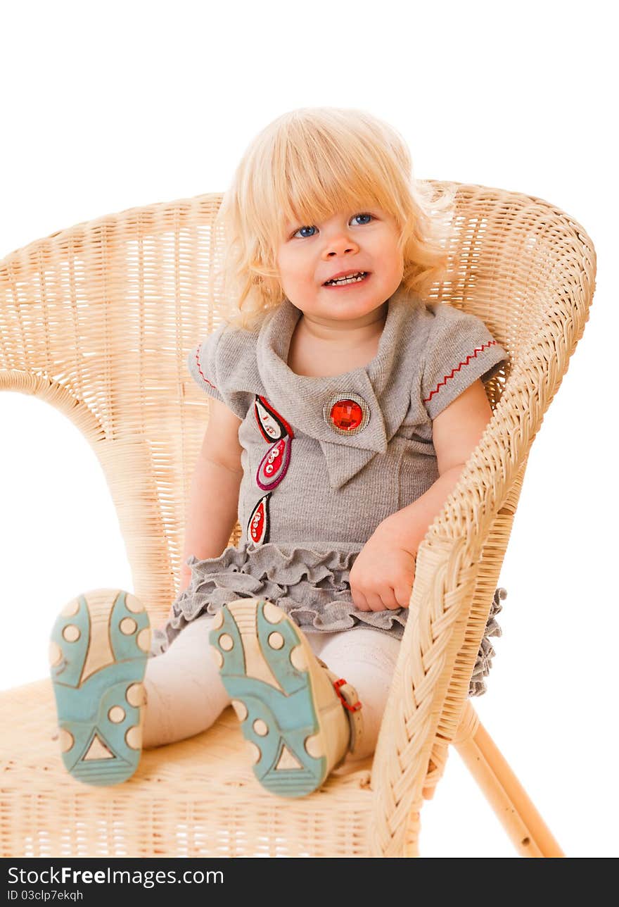 Pretty little girl sitting on wicker amchair