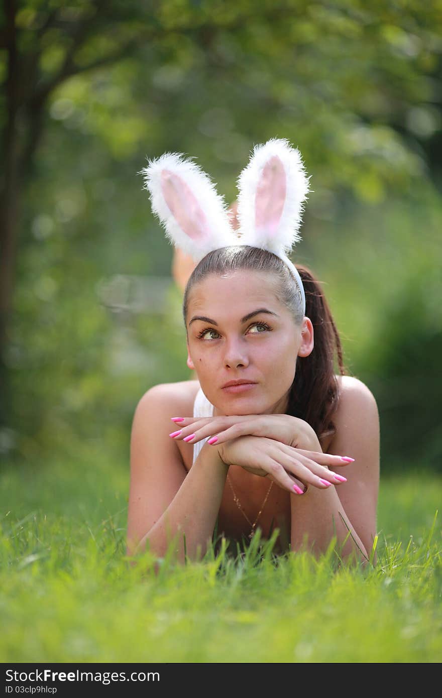 Woman with funny rabbit ears lies on a grass outdoors