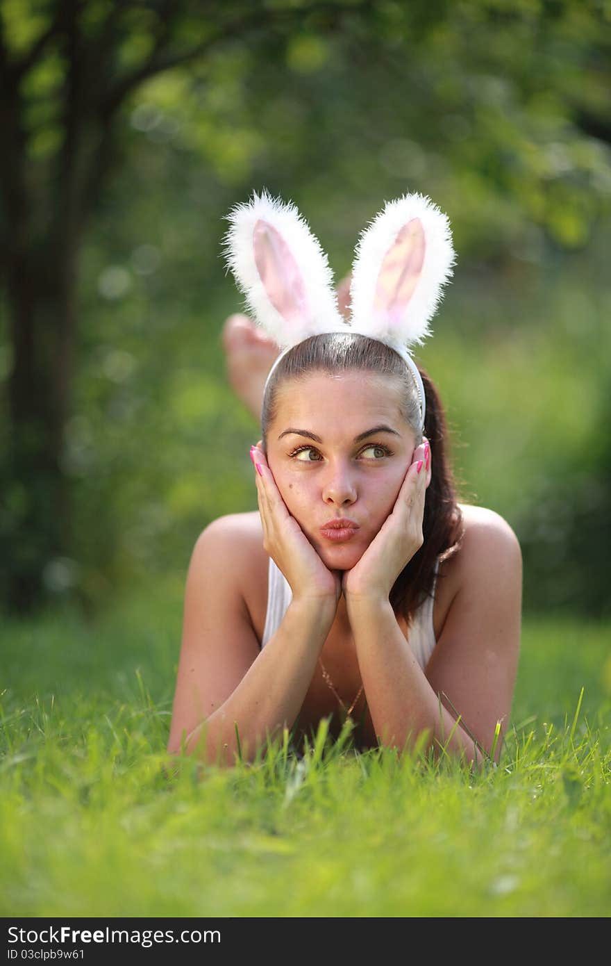 Woman with funny rabbit ears lies on a grass outdoors