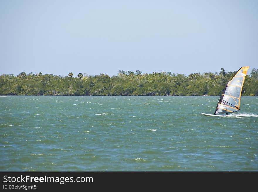 Lone windsurfer riding in from the right on an otherwise deserted lagoon. Lone windsurfer riding in from the right on an otherwise deserted lagoon.