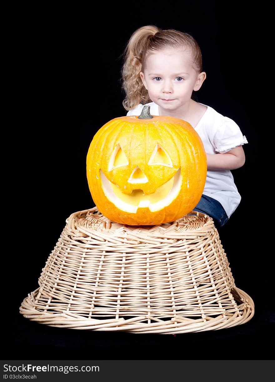 A pumpkin on a harvest basket with a child kneeling behind. A pumpkin on a harvest basket with a child kneeling behind.