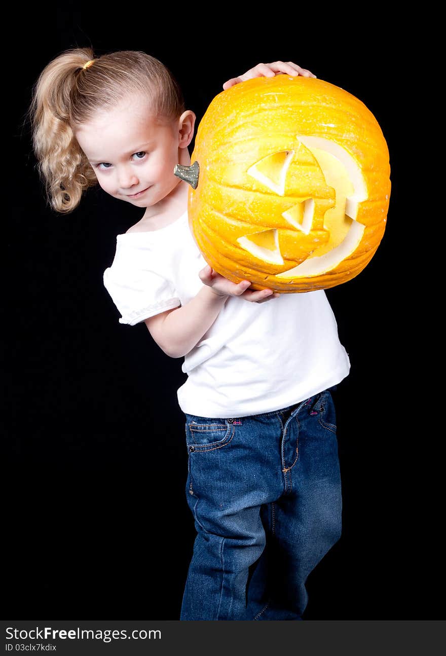 A girl is stuggling to hold up her pumpkin. The face is sideways. A girl is stuggling to hold up her pumpkin. The face is sideways.