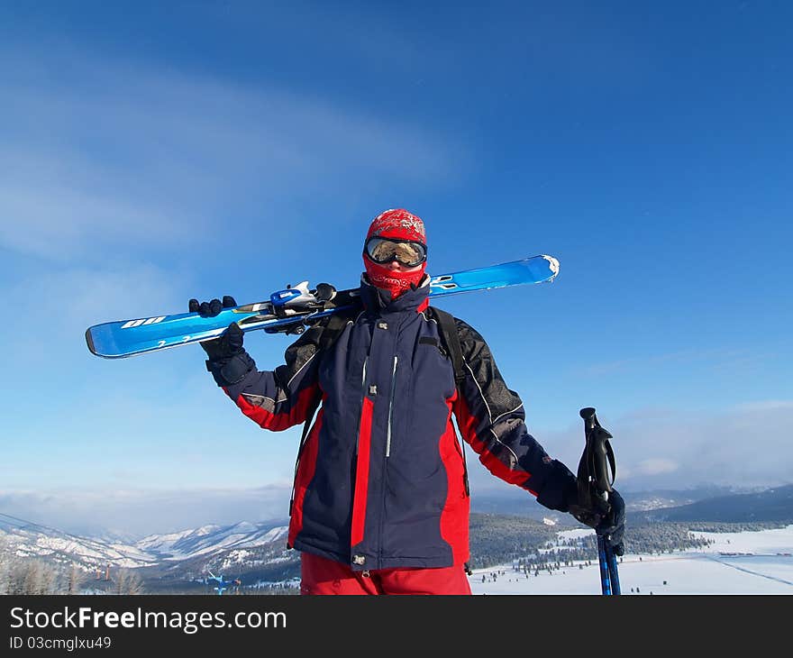 Skier in the mountains with skis on his shoulder