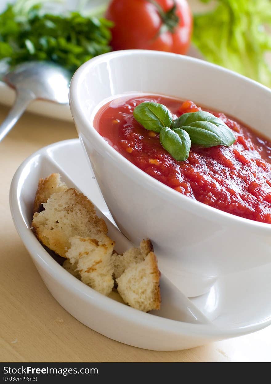 Bowl of tomato soup with bread crouton and basil