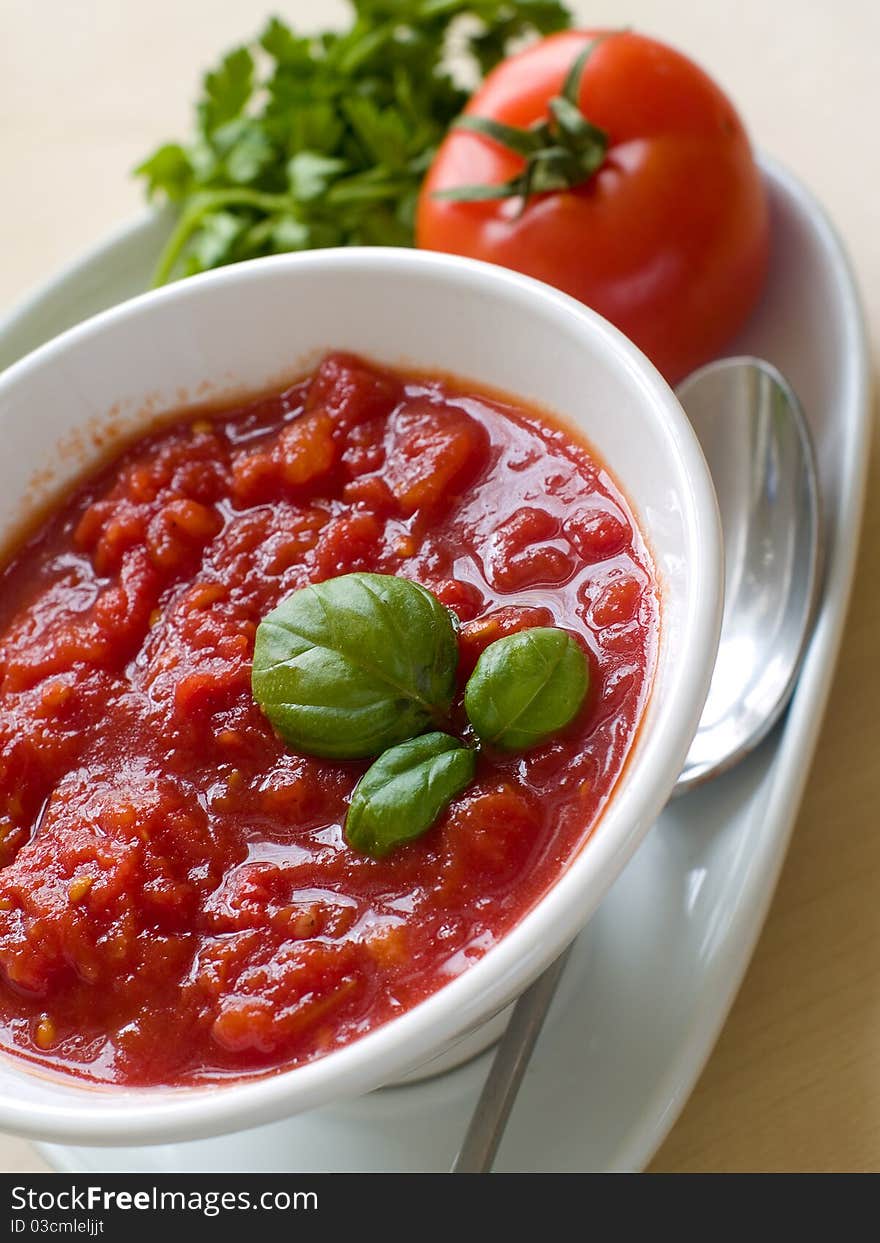 Bowl of tomato soup with bread crouton and basil