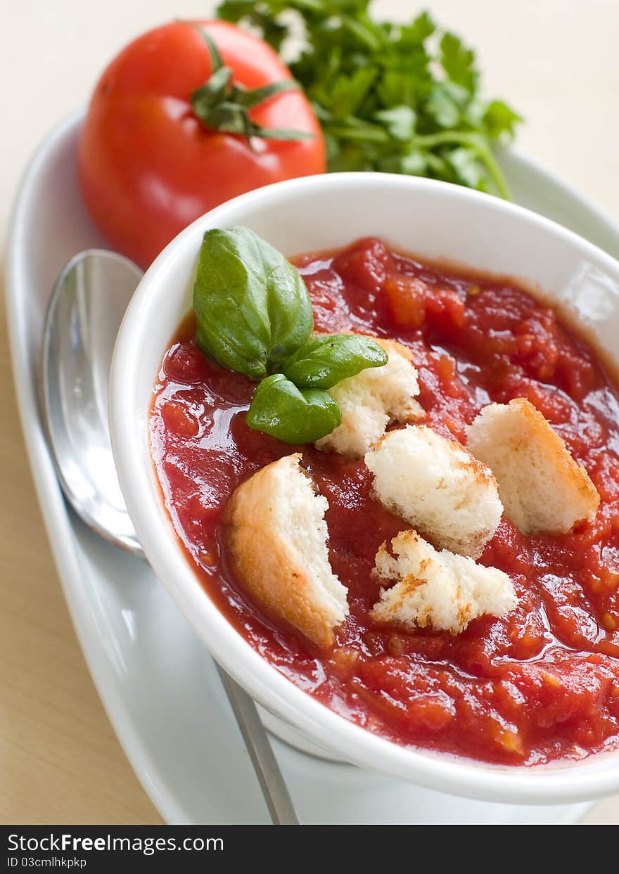 Bowl of tomato soup with bread crouton and basil