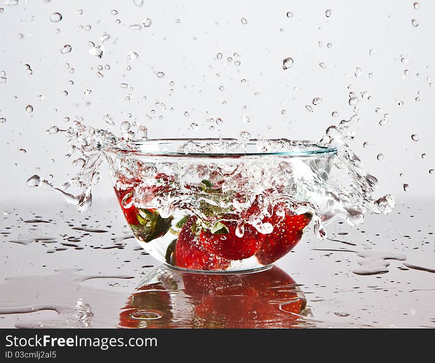 Water splashing over strawberries fallen into it. Water splashing over strawberries fallen into it