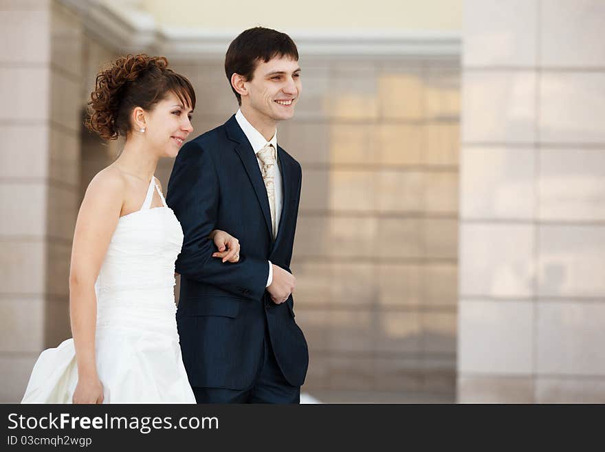 Newlyweds walking. Wall on the background