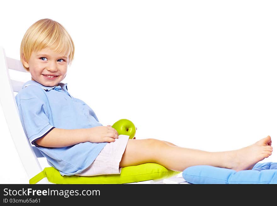 Little boy relaxing on chair with apple isolated over white back. Little boy relaxing on chair with apple isolated over white back