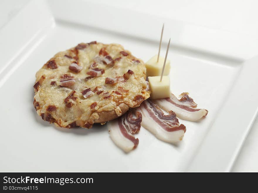 Freshly baked pastry with bacon and cheese on a square ceramic white plate