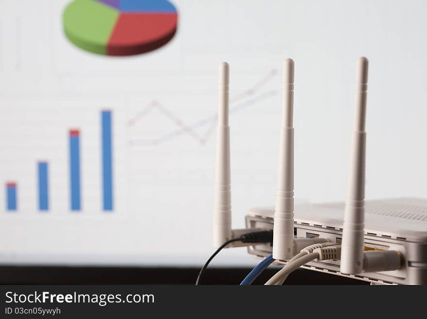 WIFI business network concept. Wireless router with plugs on foreground and business diagrams on background. Selective focus on router. WIFI business network concept. Wireless router with plugs on foreground and business diagrams on background. Selective focus on router