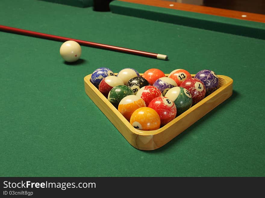 Pool stick, balls, and table used to play pool