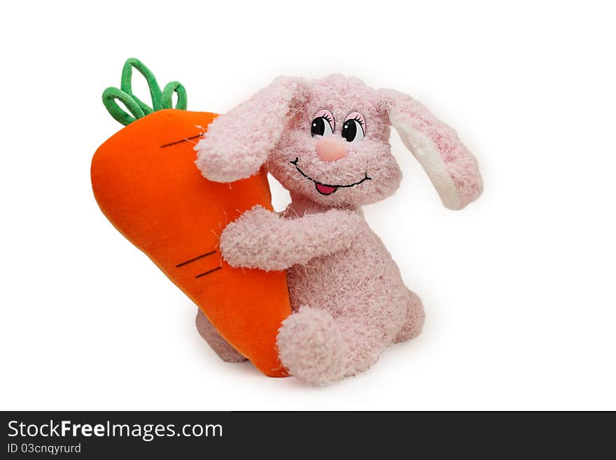 The toy pink rabbit embraces the big carrot. The toy pink rabbit embraces the big carrot