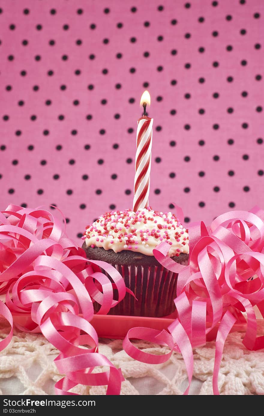 A birthday cupcake with one lit candle, selective focus, low key. A birthday cupcake with one lit candle, selective focus, low key