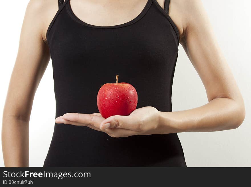 A woman with black tank top having an apple on her hand. A woman with black tank top having an apple on her hand.