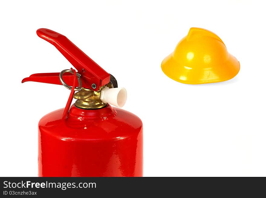 Red fire extinguisher and a yellow toy fire helmet. Concept. Red fire extinguisher and a yellow toy fire helmet. Concept