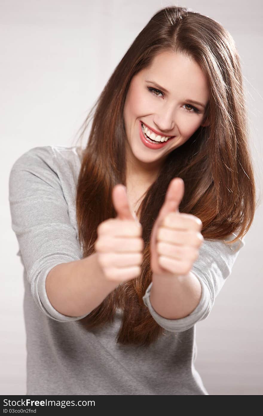 Portrait of beautiful brunette woman isolated on natural background, showing thumbs up