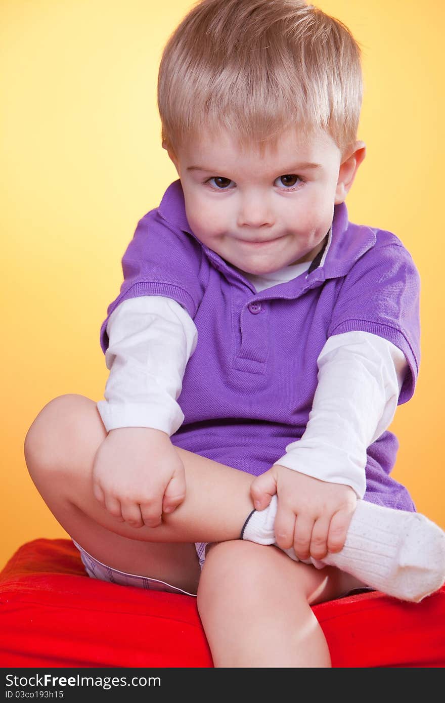 Happy smiling little boy holding leg with hands