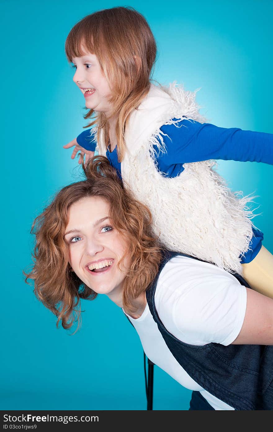 Smiling mother playing with little daughter on her shoulders. Smiling mother playing with little daughter on her shoulders