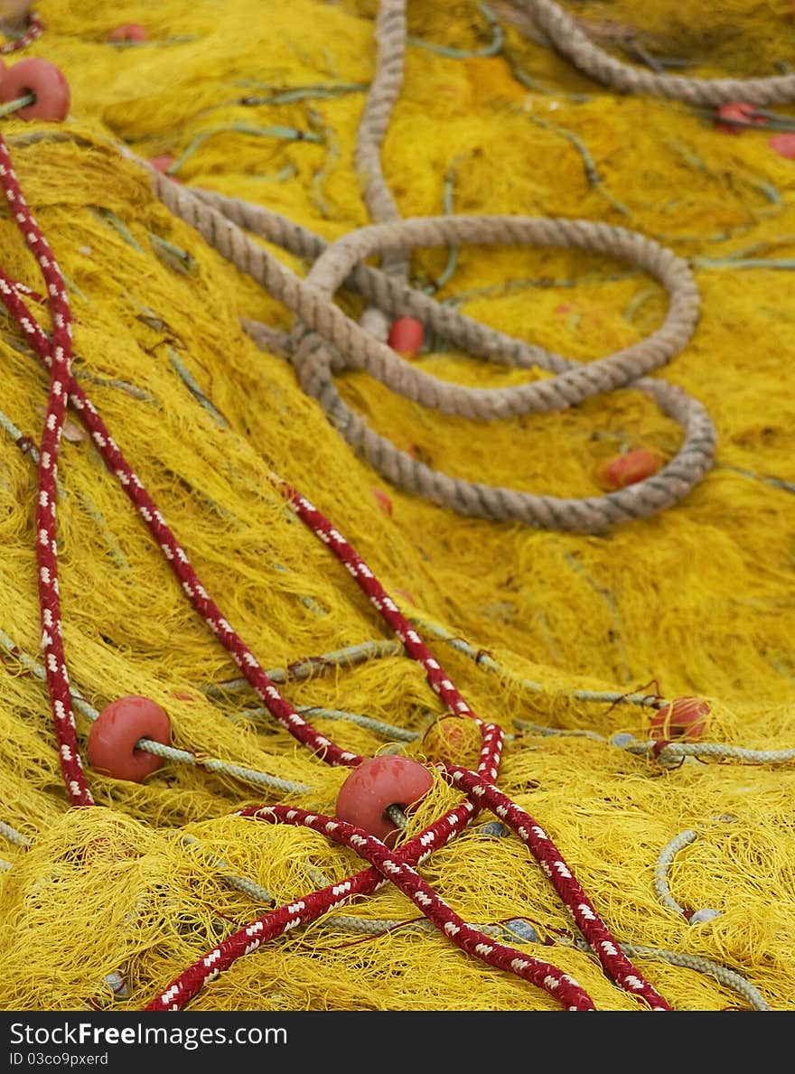 Detail image of a fishing net in front and some ropes on the back. Detail image of a fishing net in front and some ropes on the back