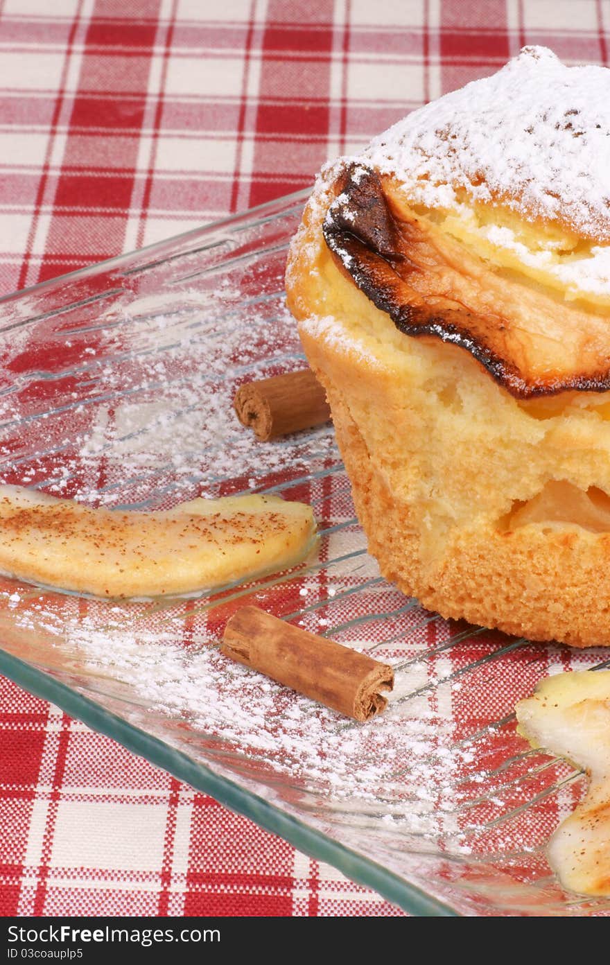 Apple muffin served on a glass plate with icing sugar, cinnamon and apple slices. Shallow DOF. Apple muffin served on a glass plate with icing sugar, cinnamon and apple slices. Shallow DOF