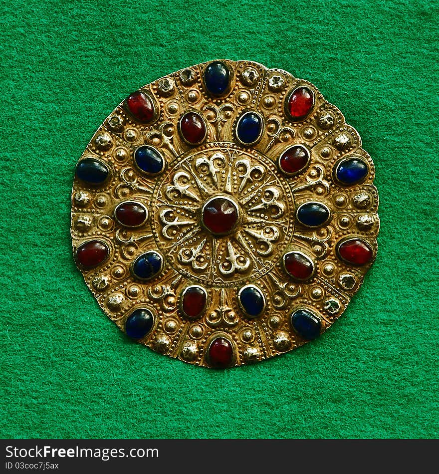 Middle-Asian vintage buckle for east dressing gown. Silver, gilding, semi-precious stones, east ornament. Isolated on dark green woollen cloth. Middle-Asian vintage buckle for east dressing gown. Silver, gilding, semi-precious stones, east ornament. Isolated on dark green woollen cloth.