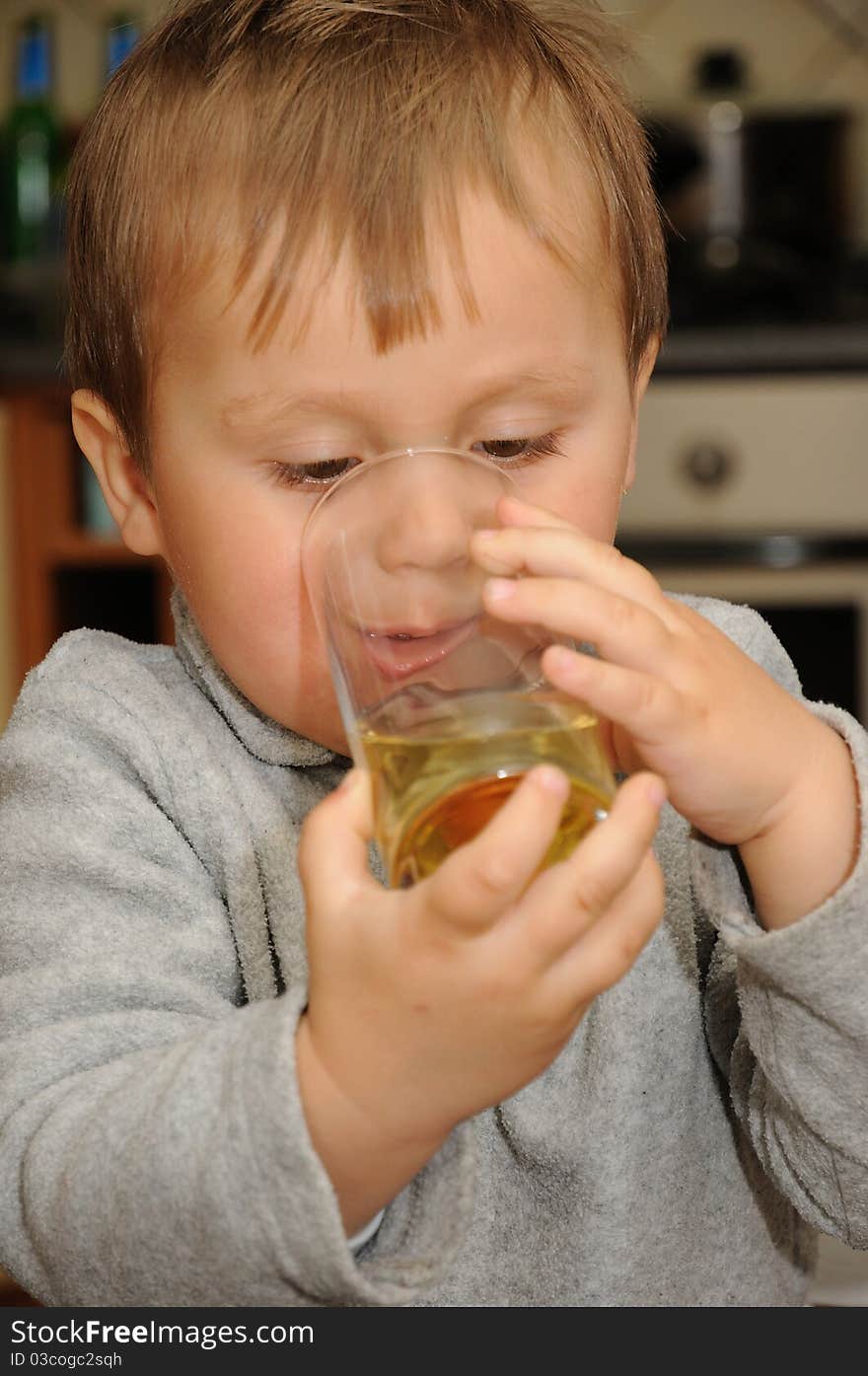 Young child holding glass of juice and drinking. Young child holding glass of juice and drinking