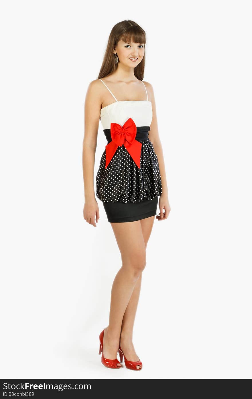 Beautiful Fashion Girl Smiling. Black skirt with white polka dots. Topic white with a red bow at the waist. Red shoes. On a white background. Full-length.