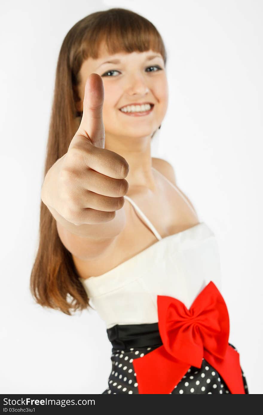 Beautiful Fashion Girl Smiling and showing thumb up. A look at the camera. Close-up. Black skirt with white polka dots. Topic white with a red bow at the waist. On a white background. Focus on foreground. Beautiful Fashion Girl Smiling and showing thumb up. A look at the camera. Close-up. Black skirt with white polka dots. Topic white with a red bow at the waist. On a white background. Focus on foreground.