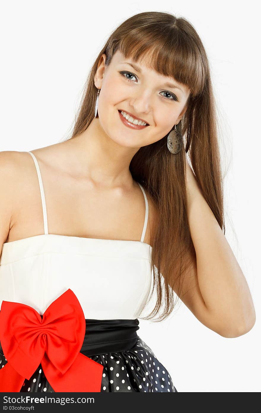 Beautiful Fashion Girl Smiling. Hand in hair. Black skirt with white polka dots. Topic white with a red bow at the waist. Close-up. On a white background.