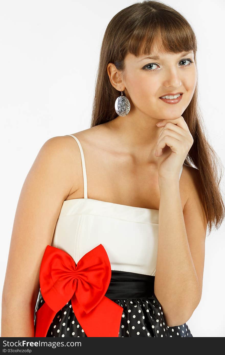 Beautiful Fashion Girl Smiling. Hand touches the chin. Black skirt with white polka dots. Topic white with a red bow at the waist. Close-up. On a white background.