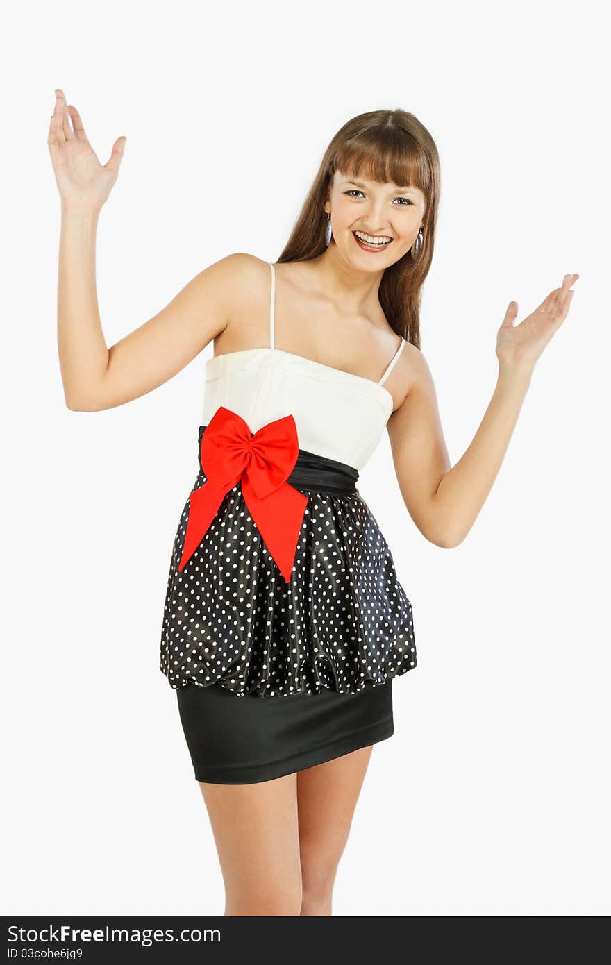 Beautiful fashion girl rejoices with her hands up. A look at the camera. Black skirt with white polka dots. Topic white with a red bow at the waist. On a white background.