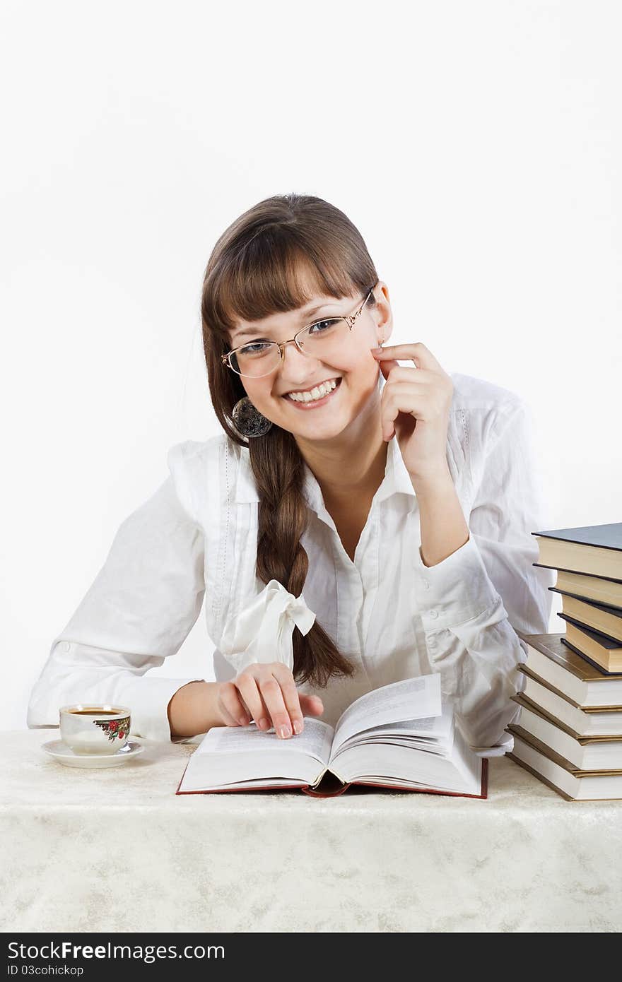 Beautiful Smiling girl reading a book at the table