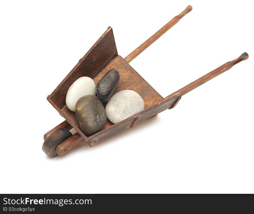 Miniature model of the wheelbarrow with stones on white