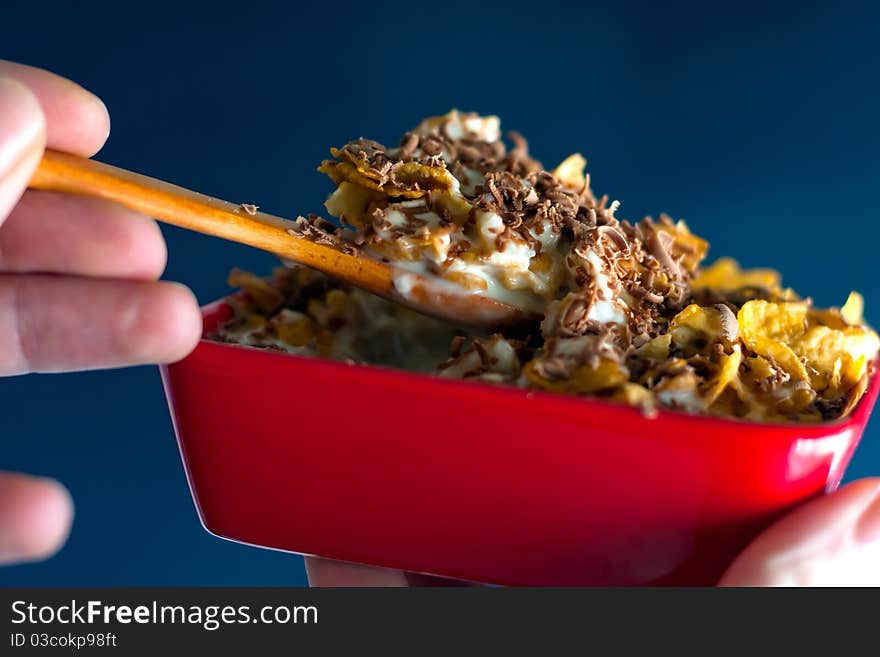 Fast and healthy breakfast. Corn flakes with milk and grated chocolate. Wooden spoon is for natural taste of this sweet food. Fast and healthy breakfast. Corn flakes with milk and grated chocolate. Wooden spoon is for natural taste of this sweet food.