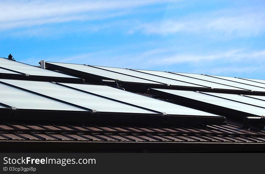 A group of solar panels on a roof on a sunny day. A group of solar panels on a roof on a sunny day.