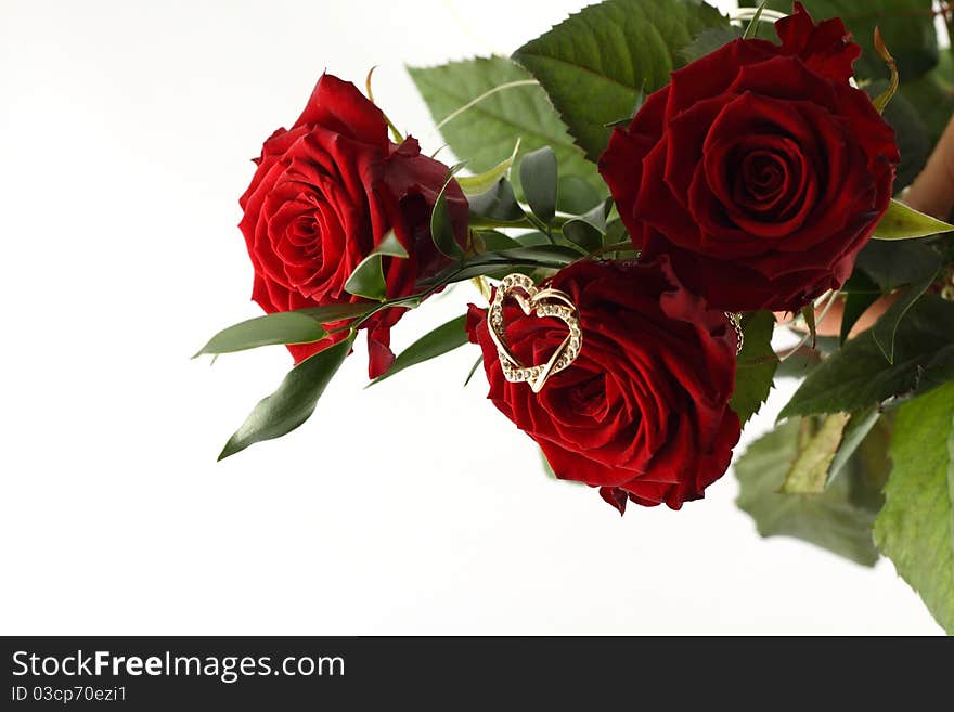 Rose bouquet and gold heart on white background.