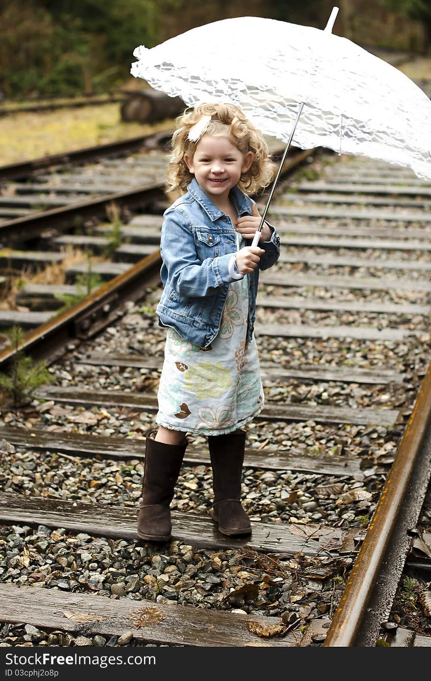 Young girl holding an umbrella while on a set of railroad tracks. Young girl holding an umbrella while on a set of railroad tracks