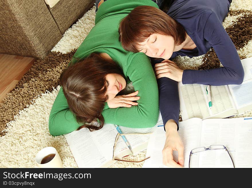 Two girls young student in a room on the floor, tired of studying and slept on textbooks. Two girls young student in a room on the floor, tired of studying and slept on textbooks