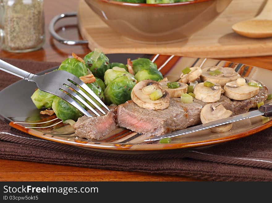 Cut piece of steak with mushrooms and brussels sprouts