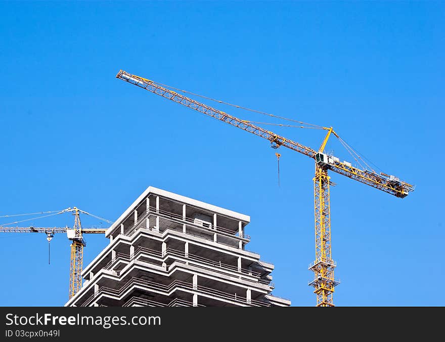 Bright yellow lift cranes on the site of high-rise building. Bright yellow lift cranes on the site of high-rise building