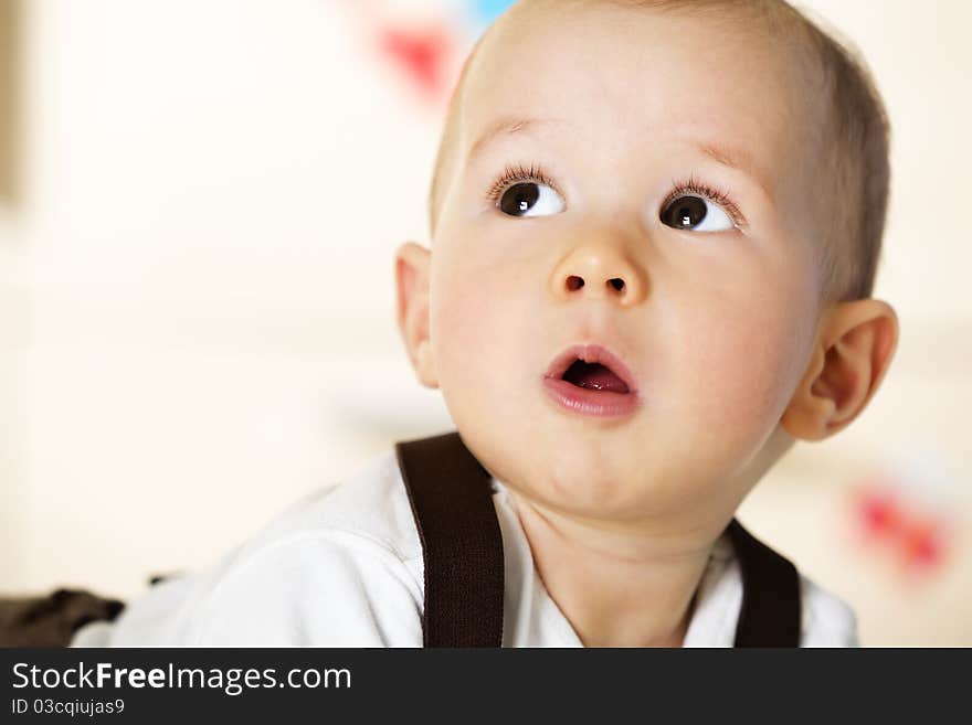 Sweet caucasian baby boy with white shirt and brown suspenders lying on floor and looking up innocently. Sweet caucasian baby boy with white shirt and brown suspenders lying on floor and looking up innocently.