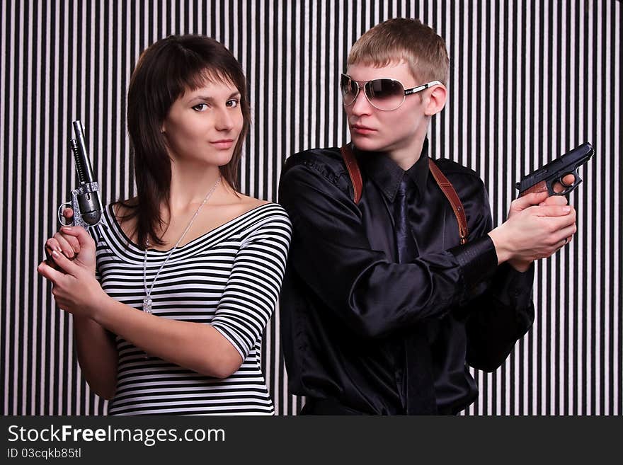 Young couple holding guns over stripe background