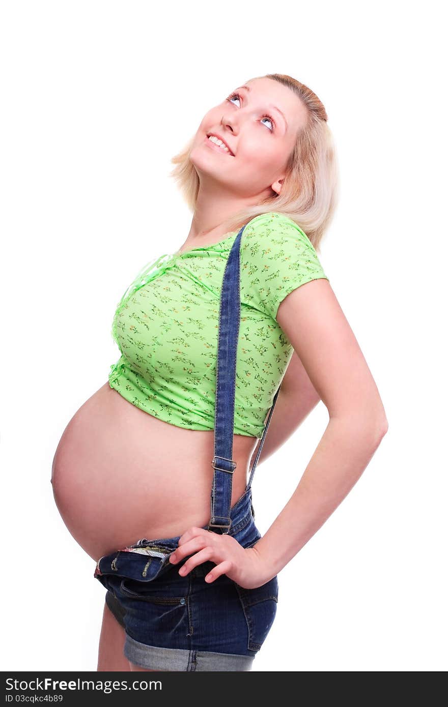 Young pretty pregnant woman posing in jeans overalls