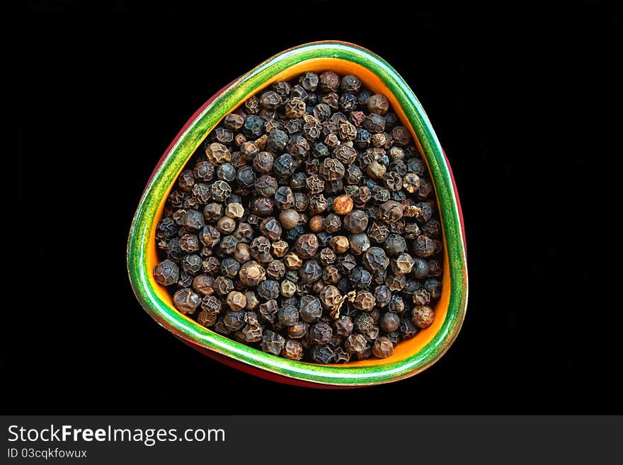 Black pepper in small ceramic bowl isolated on black background. Black pepper in small ceramic bowl isolated on black background