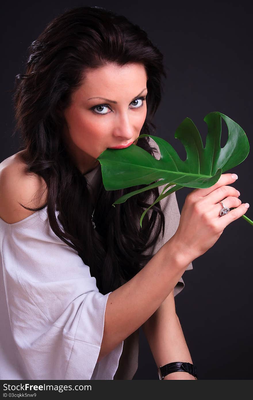 Beautiful brunette fooling around with a green leaf