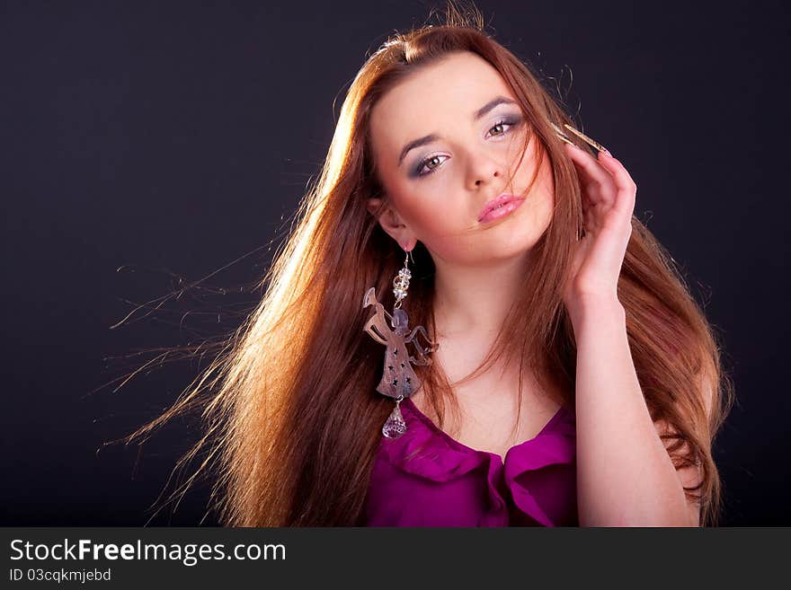 Beautiful long-haired brunette in a dress of fuchsia with sparkle earring. Beautiful long-haired brunette in a dress of fuchsia with sparkle earring