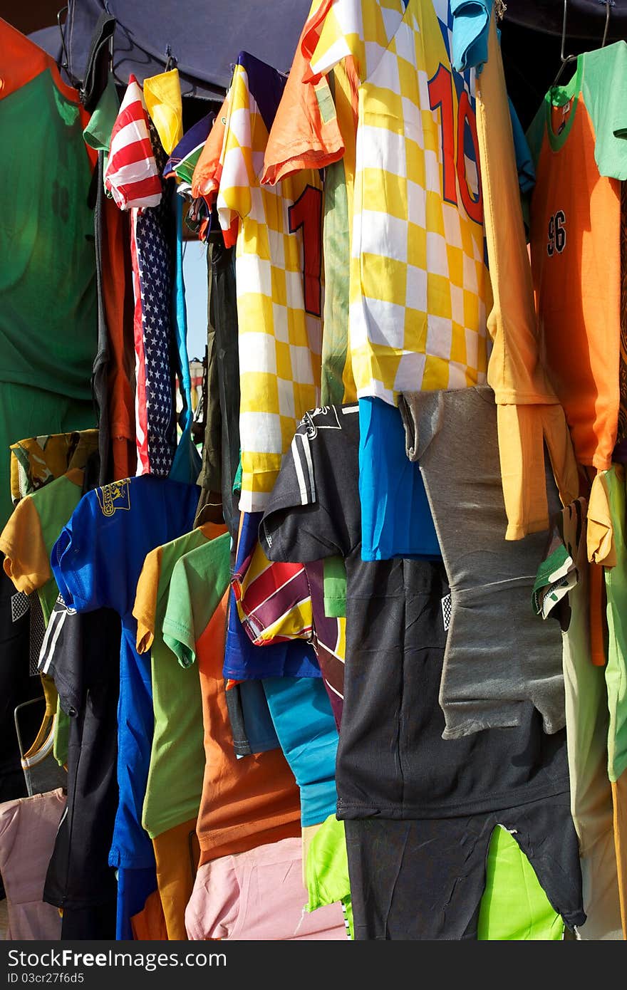 A selection of colorful t-shirts hanging on a rack in the market of Mopti in Mali