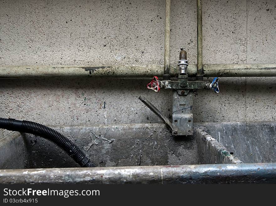 Piping, plumbing and faucet surrounding an industrial, concrete sink. Piping, plumbing and faucet surrounding an industrial, concrete sink.